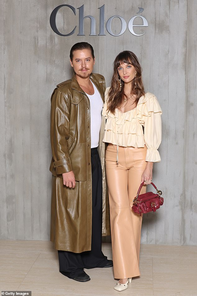 Cole Sprouse wore a long leather trench coat as he posed beside his model girlfriend Ari Fournier