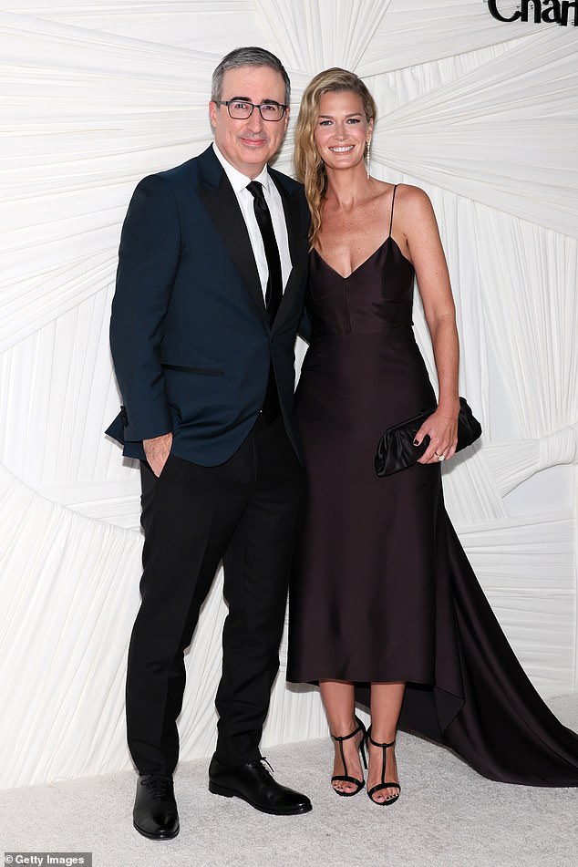 John Oliver donned a dark teal suit jacket and black slacks as he was joined by Kate Norley who was classy in a black dress that contained a long train that flowed behind her