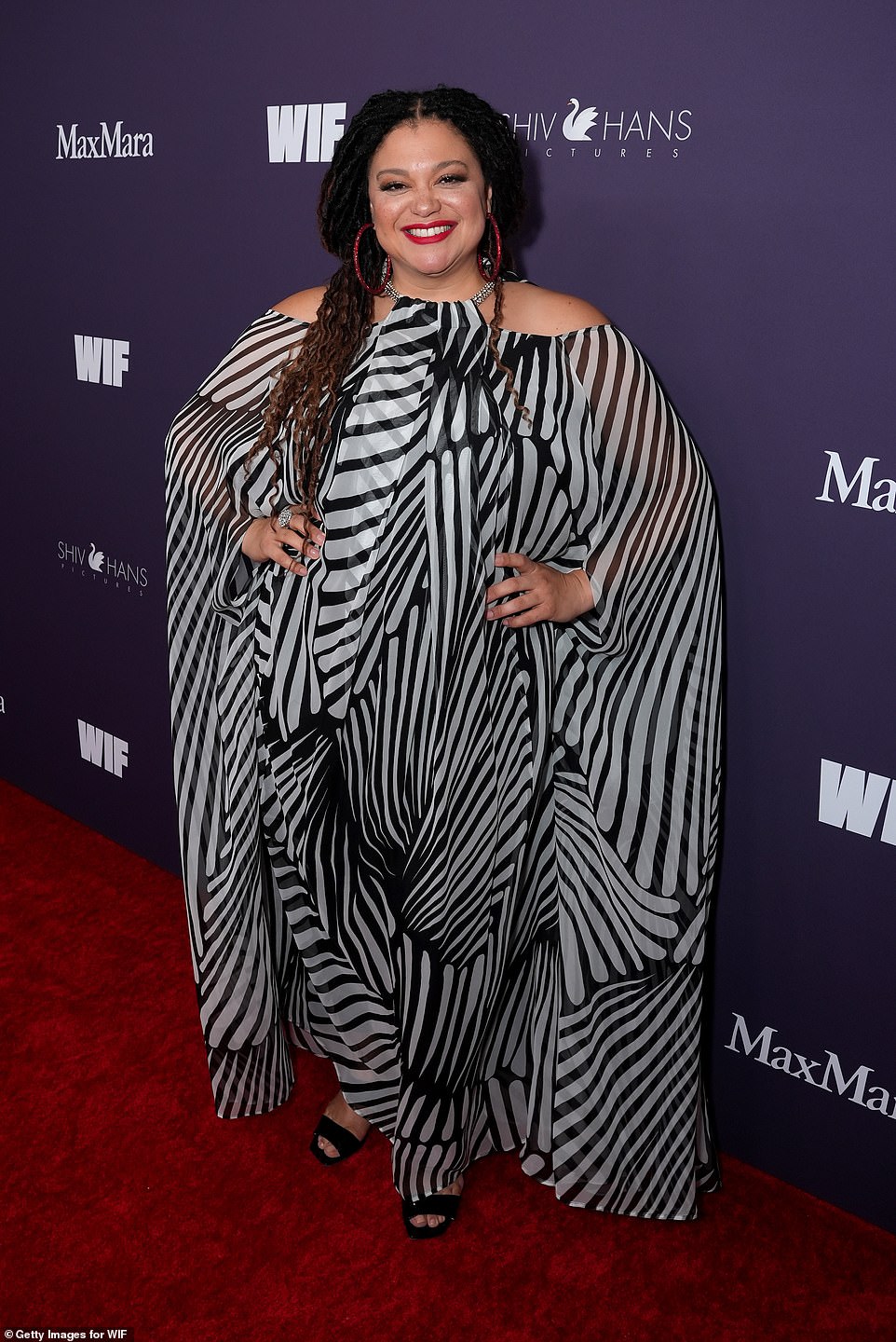 Michelle Buteau looked sensational in a flowing black and white kaftan. For a fun pop of color, the star of Babes, 47, threw on some sparkly red hoop earrings