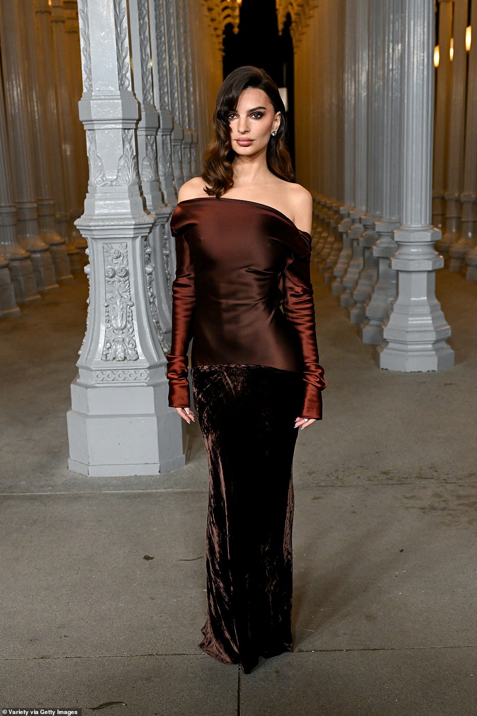 At the soirée, Emily Ratajkowski, 33, also put on a show-stopping display in a fabulous dress. The brunette bombshell donned a reddish-brown, silk gown with off-the-shoulder, long sleeves and a velvet, drop skirt