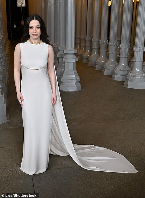 Mikey Madison put on an elegant display in a white, sleeveless dress with a long, floor-sweeping cape trailing behind her