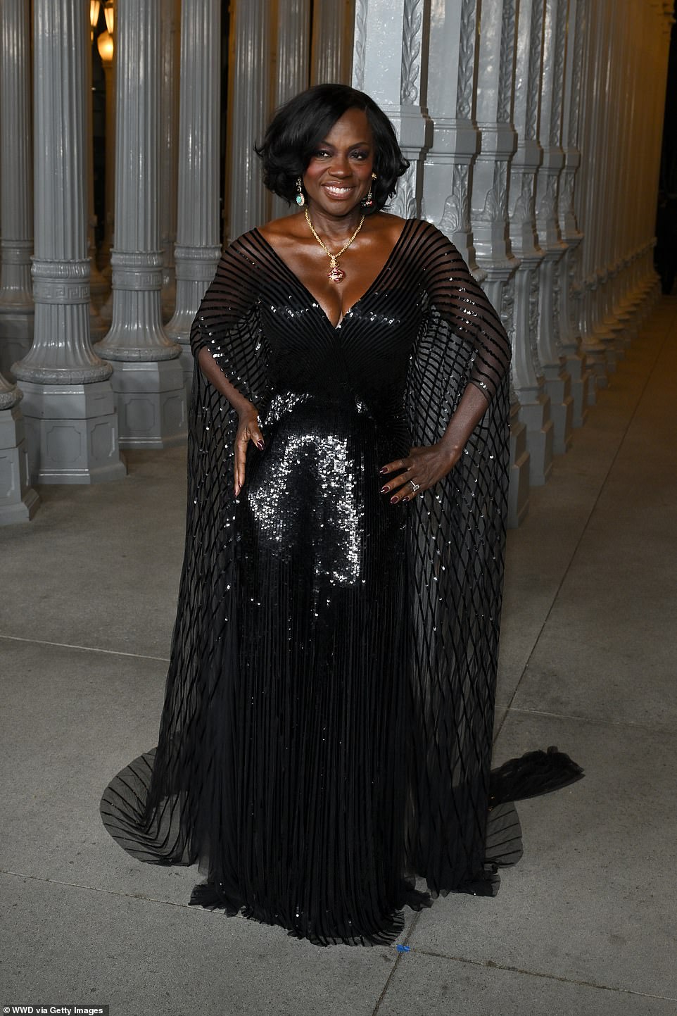 The EGOT-winning actress, 59, took the plunge in a figure-hugging gown with dramatically long sleeves that transformed into a cape cascading down behind her. Teamed with the sparkly gown, she accessorized with a striking, gold pendant necklace and stunning gemstone earrings