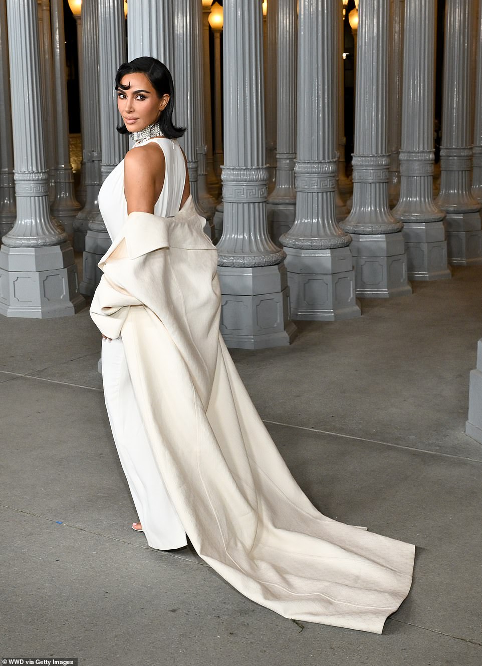 As she walked, her long, cream-colored coat trailed behind her like a train