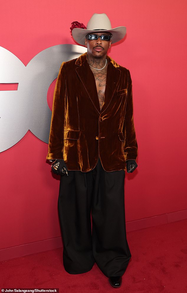 YG turned heads wearing an oversized, dark gold velvet blazer as well as a pair of baggy pants. He added a tan hat on top of his head that also contained a red, feather detail