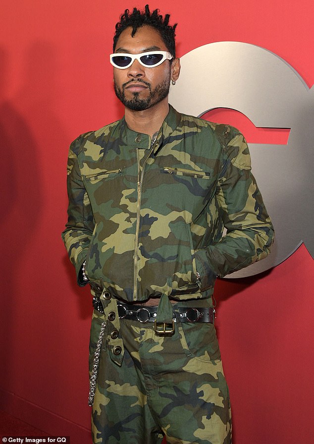 Miguel wore a green, camouflage jacket as well as a pair of matching pants and white-rimmed shades