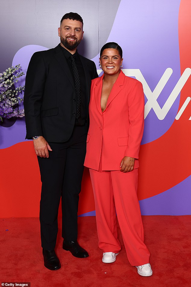 Madison Prespakis of the Bombers went for a bright coral suit in a loose fit paired with white sneakers as she posed with her date in black