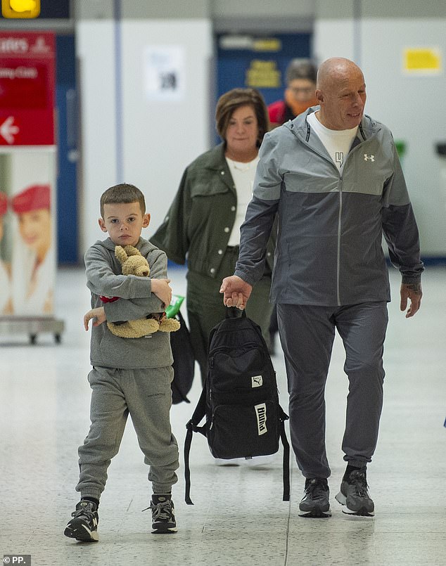 The boys, in matching grey tracksuits, clutched their toys as they made their way through departures