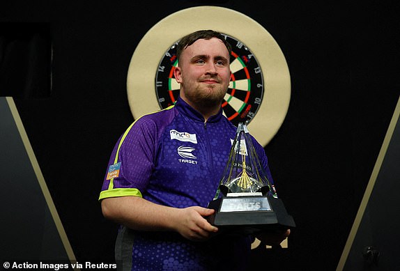 FILE PHOTO: Darts - 2024 Premier League - Play-Offs - London - The O2, London, Britain - May 23, 2024 Luke Littler celebrates with a trophy after winning his final match against Luke Humphries Action Images via REUTERS/Matthew Childs/File Photo