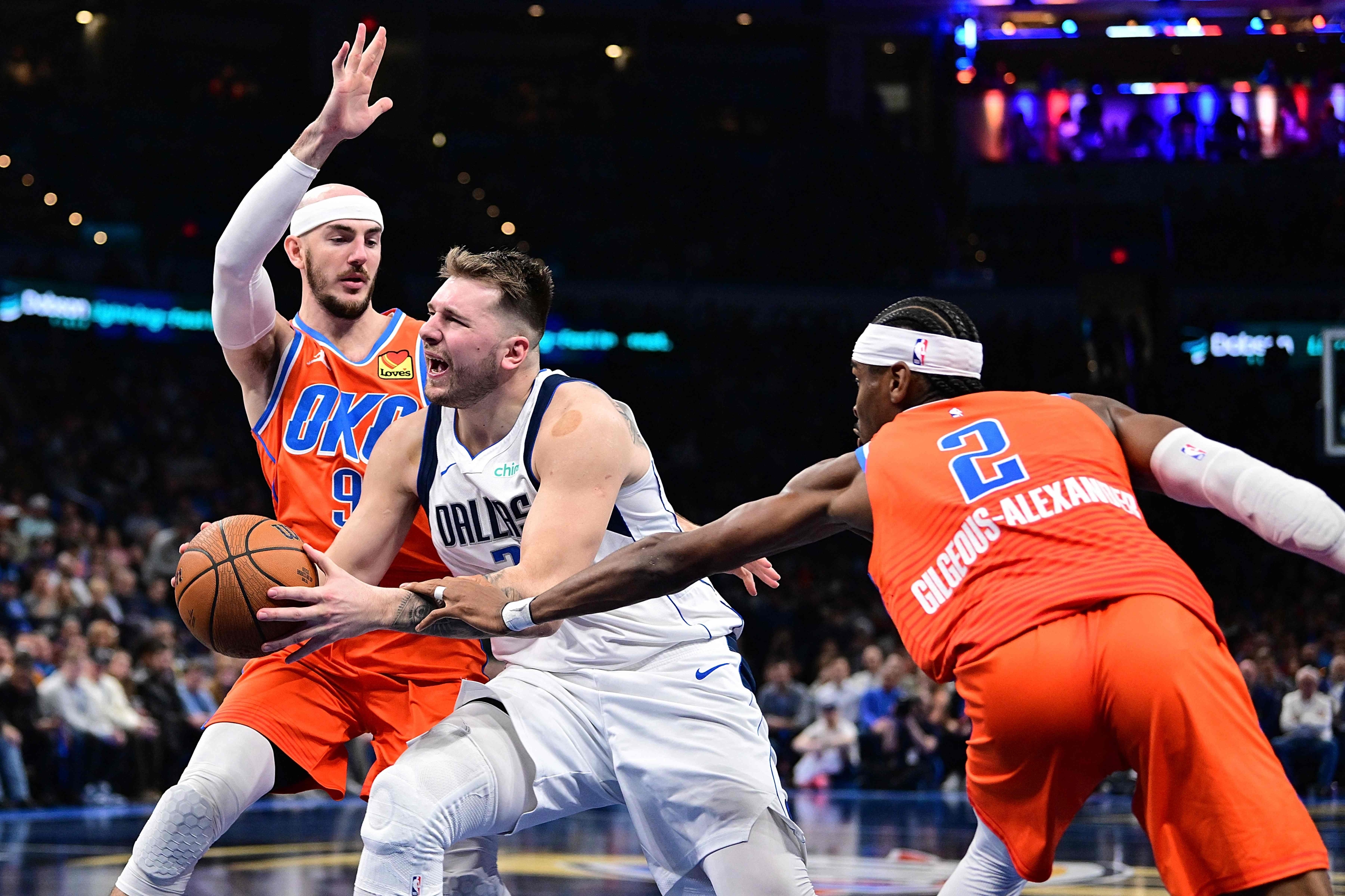 OKLAHOMA CITY, OKLAHOMA - 10. PROSINCA: Luka Dončić broj 77 iz Dallas Mavericksa pokušava voziti pored Shai Gilgeous-Alexandera #2 i Alexa Carusa #9 iz Oklahoma City Thundera tijekom drugog poluvremena u Paycom Centru 10. prosinca 2024. u Oklahomi City, Oklahoma. NAPOMENA ZA KORISNIKA: Korisnik izričito potvrđuje i slaže se da preuzimanjem i/ili korištenjem ove fotografije Korisnik pristaje na odredbe i uvjete Licencnog ugovora Getty Images. Joshua Gateley/Getty Images/AFP (Fotografija Joshua Gateley/GETTY IMAGES SJEVERNA AMERIKA/Getty Images putem AFP-a)