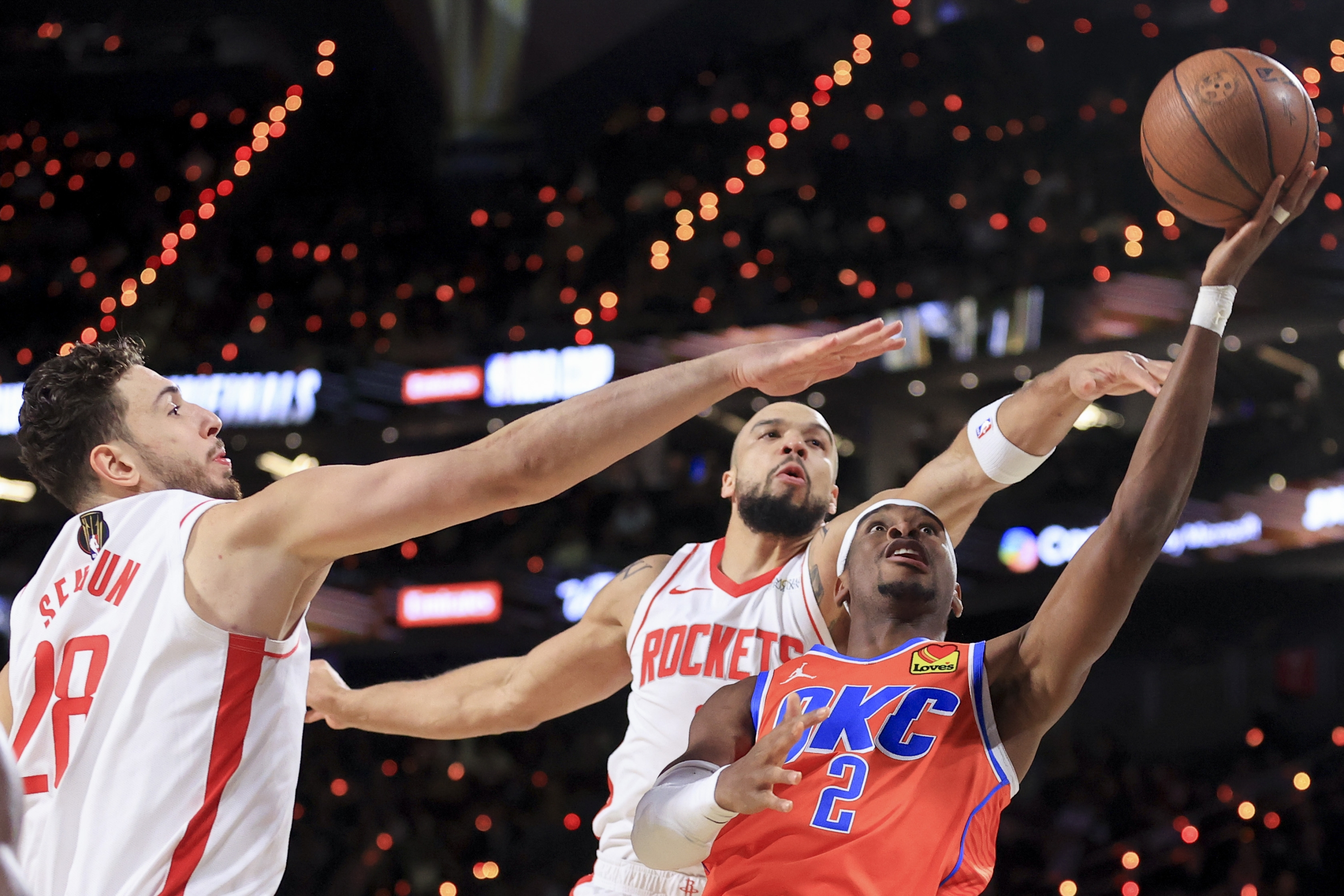 Čuvar Oklahoma City Thundera Shai Gilgeous-Alexander (2) puca protiv centra Houston Rocketsa Alperena Senguna (28) i napadača Dillona Brooksa, stražnji desno, tijekom prvog poluvremena polufinalne utakmice na košarkaškom turniru NBA kupa u subotu, 14. prosinca 2024. , u Las Vegasu. (AP Photo/Ian Maule)