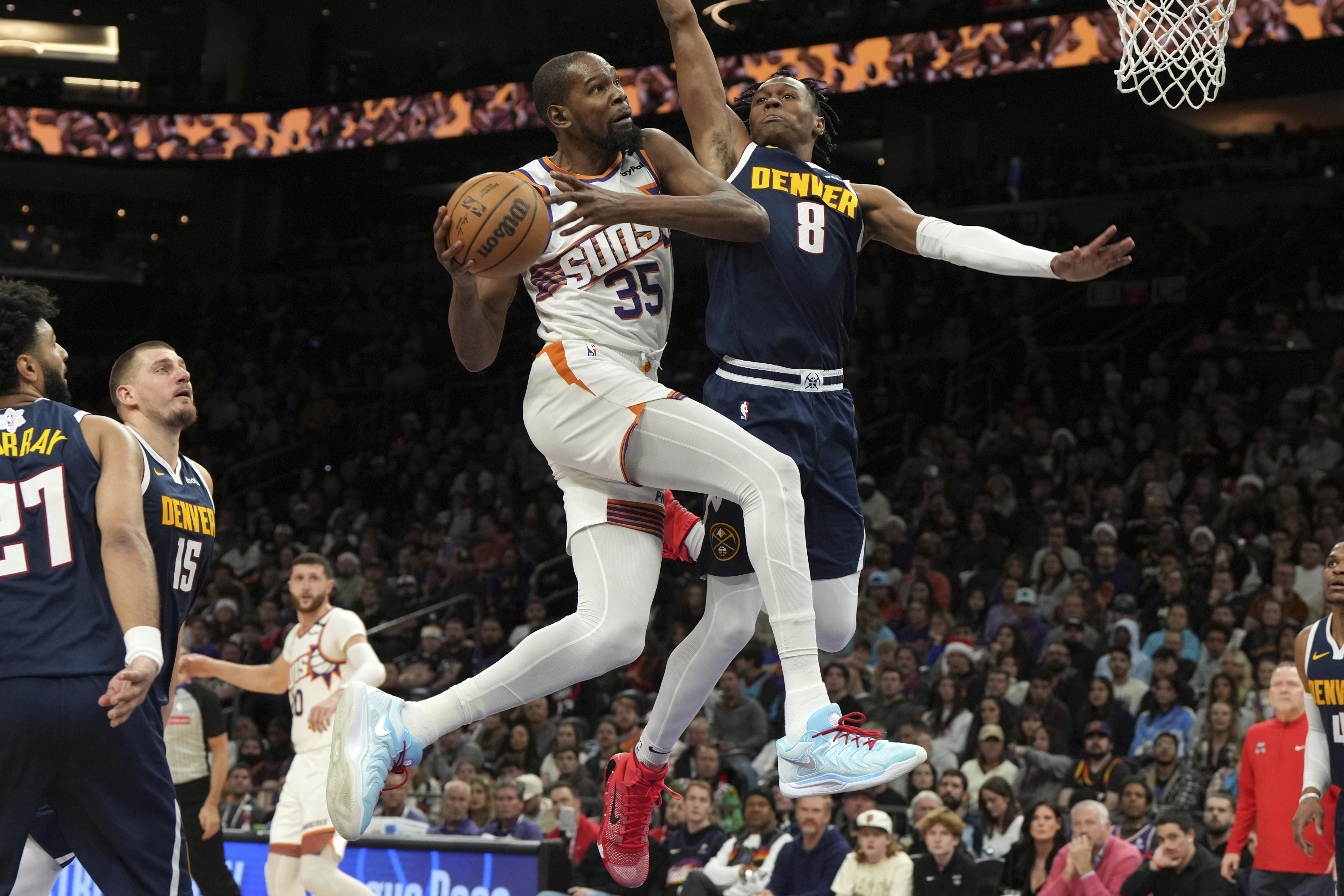 Napadač Phoenix Sunsa Kevin Durant (35) vozi protiv napadača Denver Nuggetsa Peytona Watsona (8) tijekom drugog poluvremena NBA košarkaške utakmice, srijeda, 25. prosinca 2024., u Phoenixu. Phoenix je pobijedio 110-100. (AP Photo/Rick Scuteri)