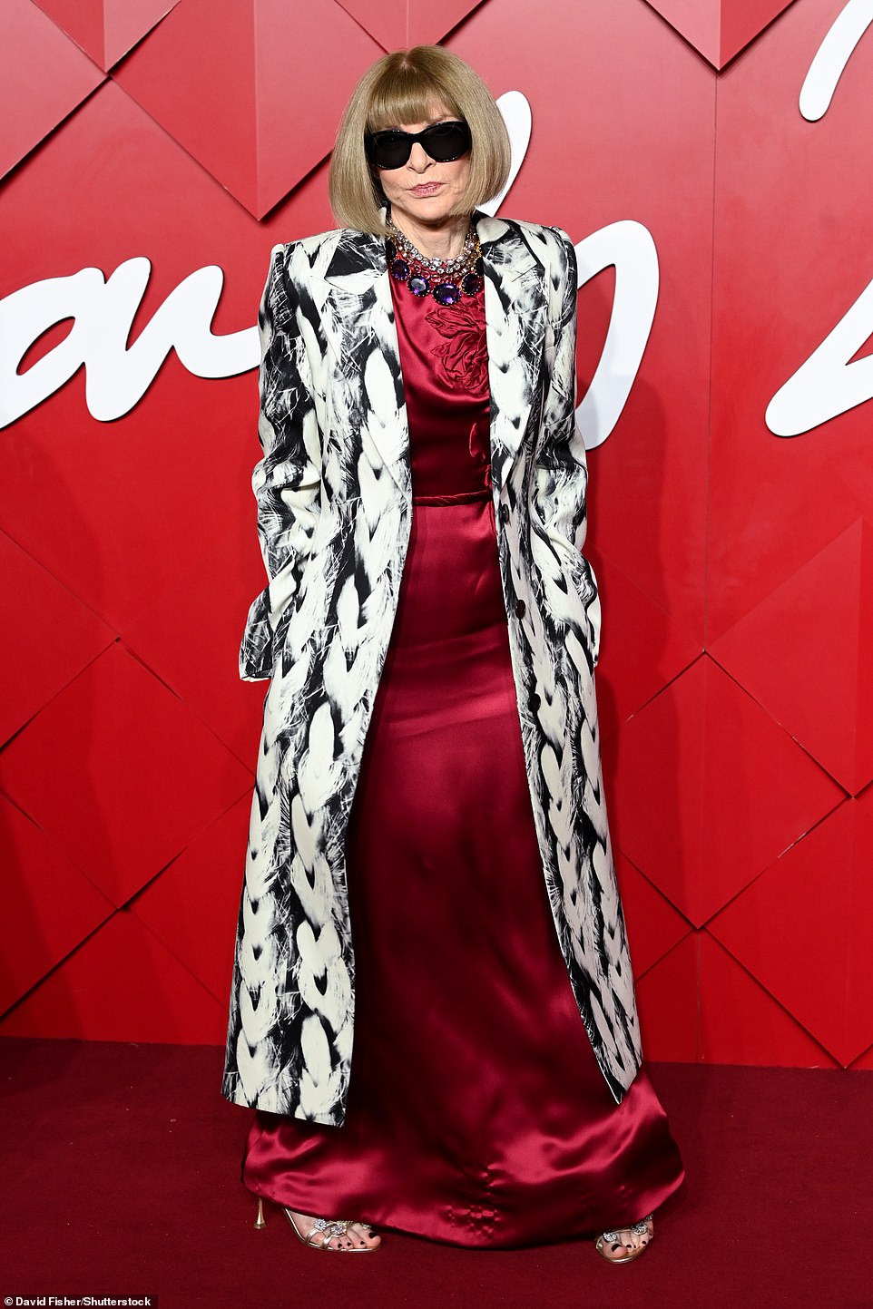 Anna Wintour wore her signature shades as she wowed in a silk red dress and quirky black and white patterned coat