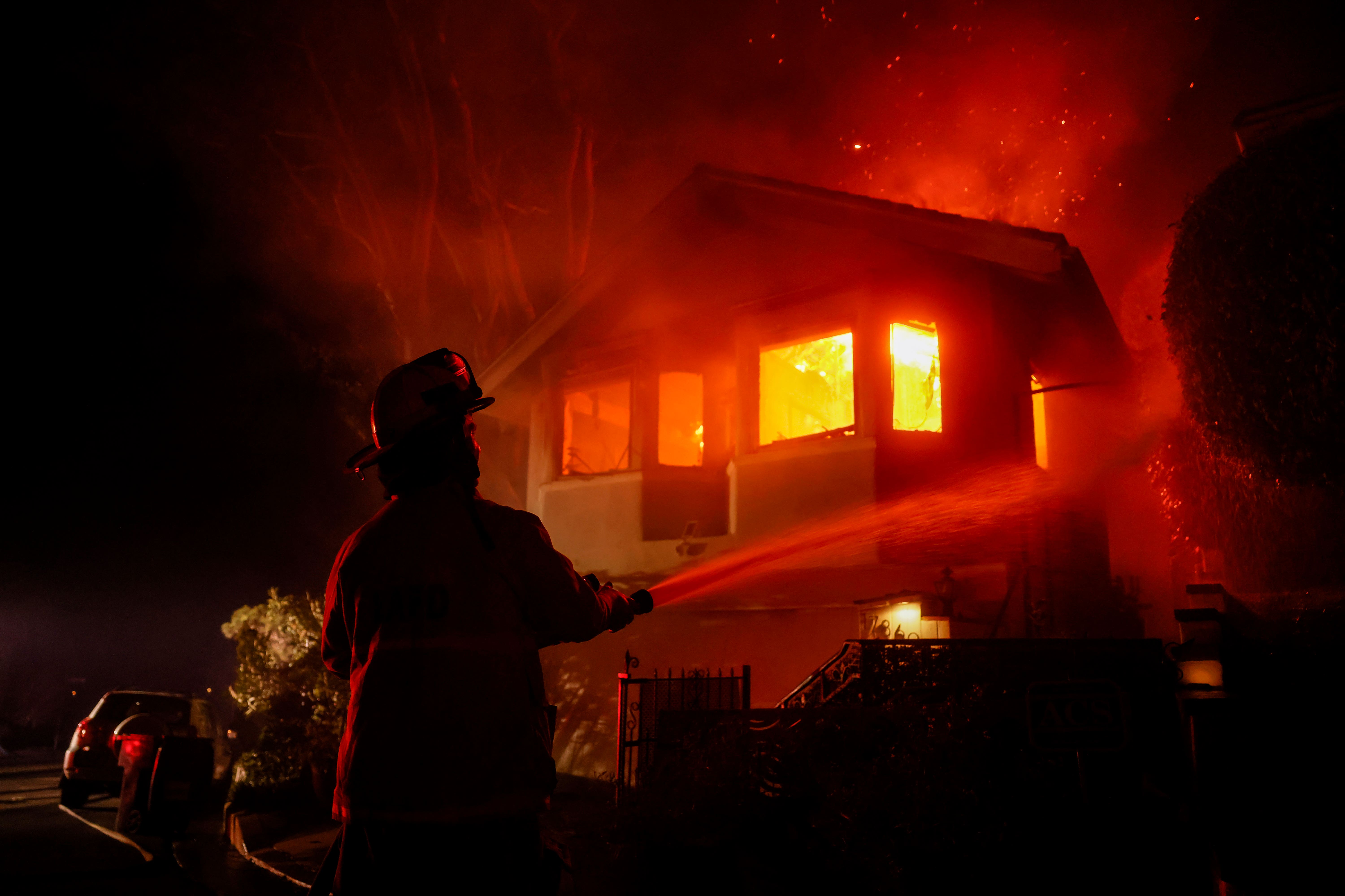 Vatrogasac radi dok Palisades Fire spaljuje kuću u brdu pokraj vile Getty. Prema izvješćima, oko 30 posto državnih snaga za gašenje požara dolaze od zatvorenika