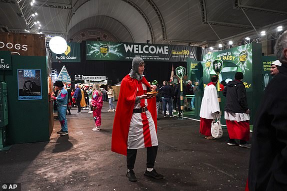 Fans dressed in costumes are seen around the fan village before the start of the quarter final match between Peter Wright of Scotland and Stephen Bunting of England, at the World Darts Championship in London, Wednesday, Jan. 1, 2025.(AP Photo/Alberto Pezzali)