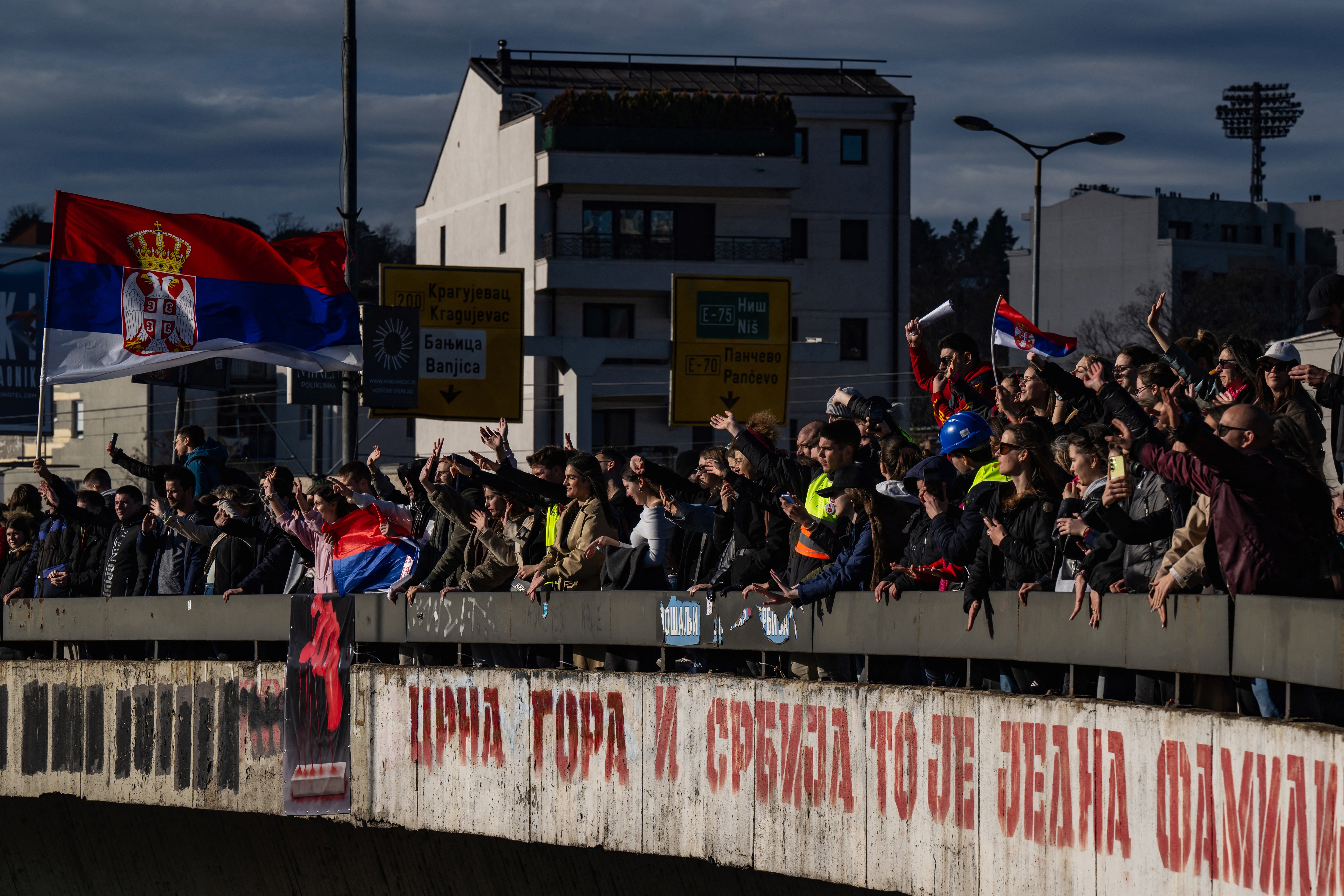 Prosvjednici drže nacionalne zastave i mahnu iz mosta iznad autoceste