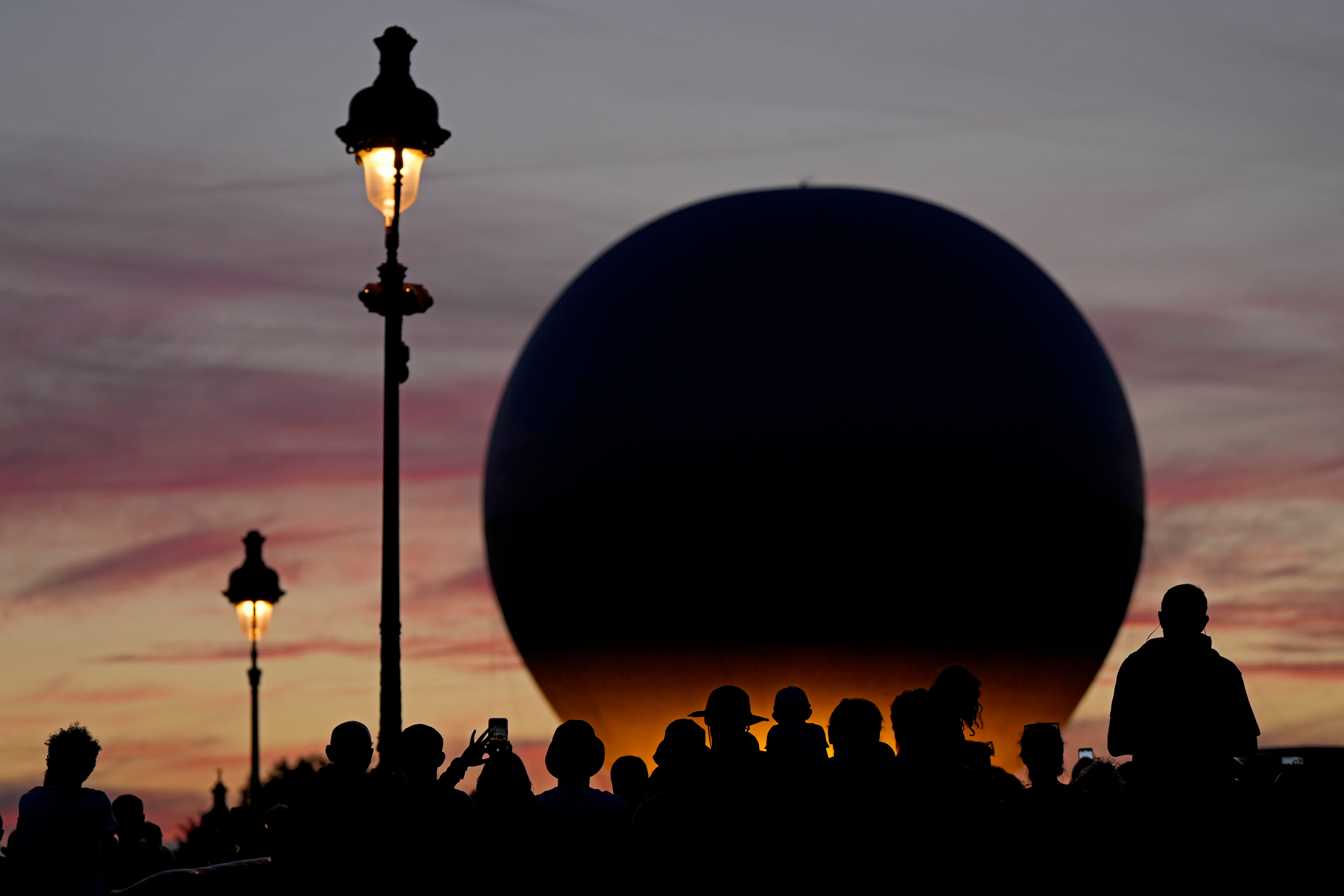Ljudi čekaju da se balon koji nosi olimpijski kotlog uzdizao iznad vrta Tuileries tijekom ljetnih olimpijskih igara 2024. godine