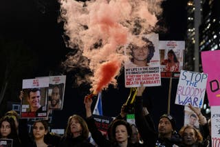 Prosvjednici drže fotografije talaca i dimnu baklju tijekom demonstracija pozivajući na povratak talaca koje drži Hamas