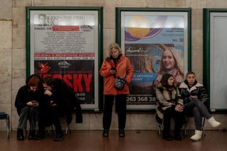 Žena provjerava svoj telefon dok se stanovnici sklanjaju na stanici metroa u Kijevu