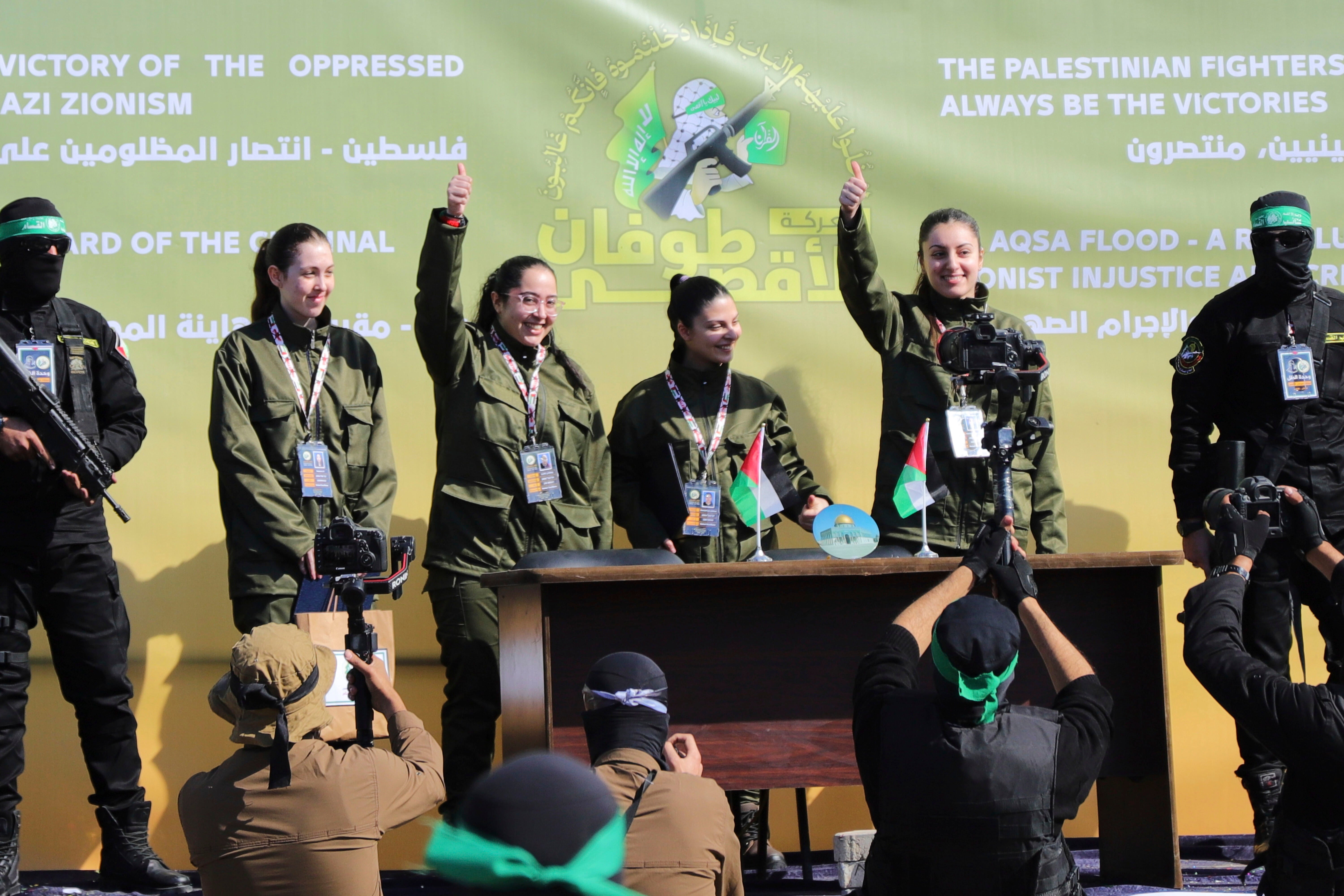 The four were led onto a podium in Gaza City where they waved and smiled amid a large crowd of Palestinians and surrounded by dozens of armed Hamas men before being led off