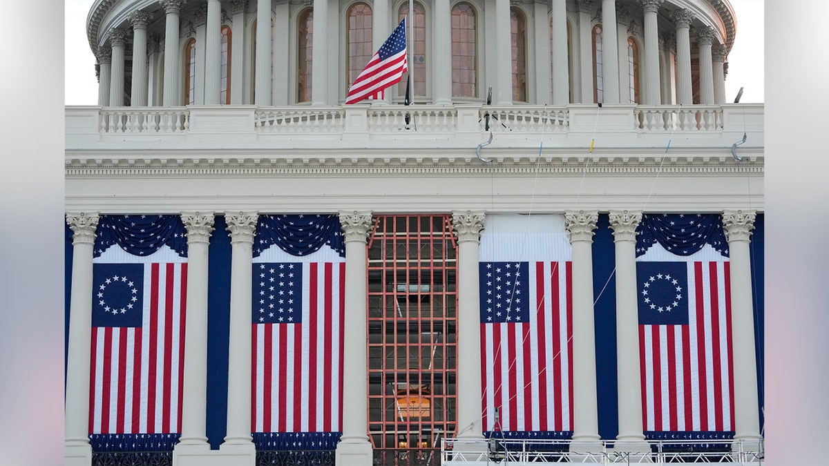 Pogled na Bijelu kuću s američkim zastavama okačenim između stupova.