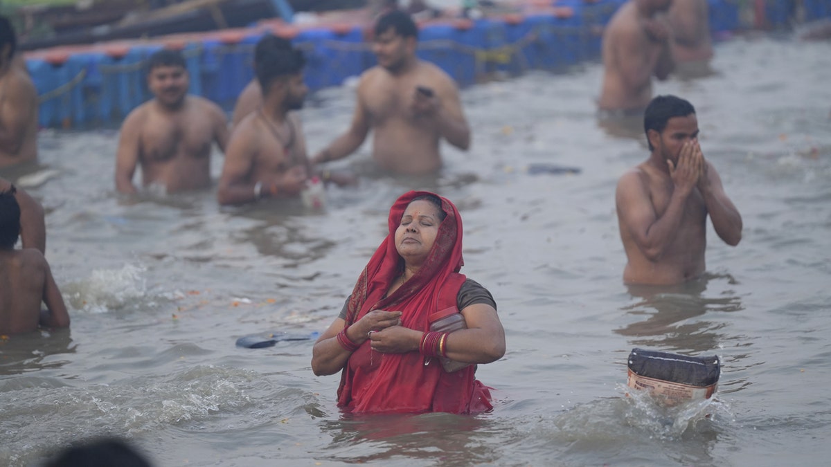 Hinduistička žena odjevena u crveno uzima sveti uranja u svete vode.