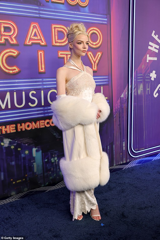 Slojila je svoj elegantni jednodijelni pod ogromnim bijelim pahuljastim kaputom, koji je pustila da joj padne niz ruke