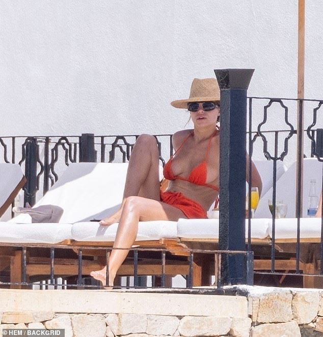 Dok je sunčala, ona je oklopila lice od zraka širokim kaputama od slame i crnim, omotanim sunčanim naočalama