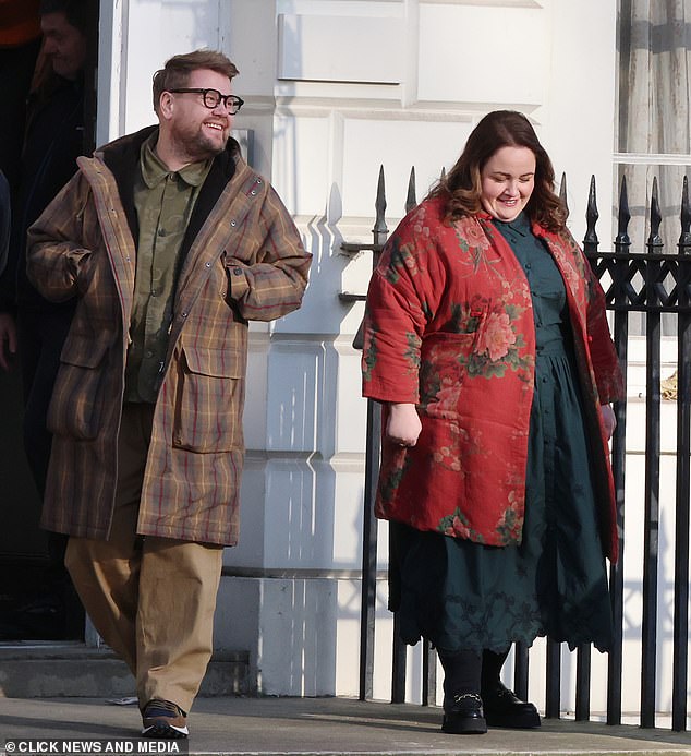 Jessica je udružila zelenu haljinu košulje s cvjetnim posljedicama, udružena s crvenim tiskanim kaputom