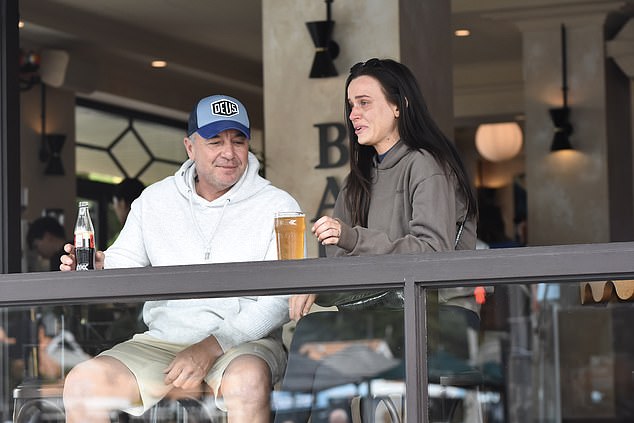 Tony, odjeven u sivu kapuljaču, bež kratke hlače i plavu bejzbol kapu, sjedila je pored nje, izgledajući opušteno, ali angažirano u njihovom razgovoru