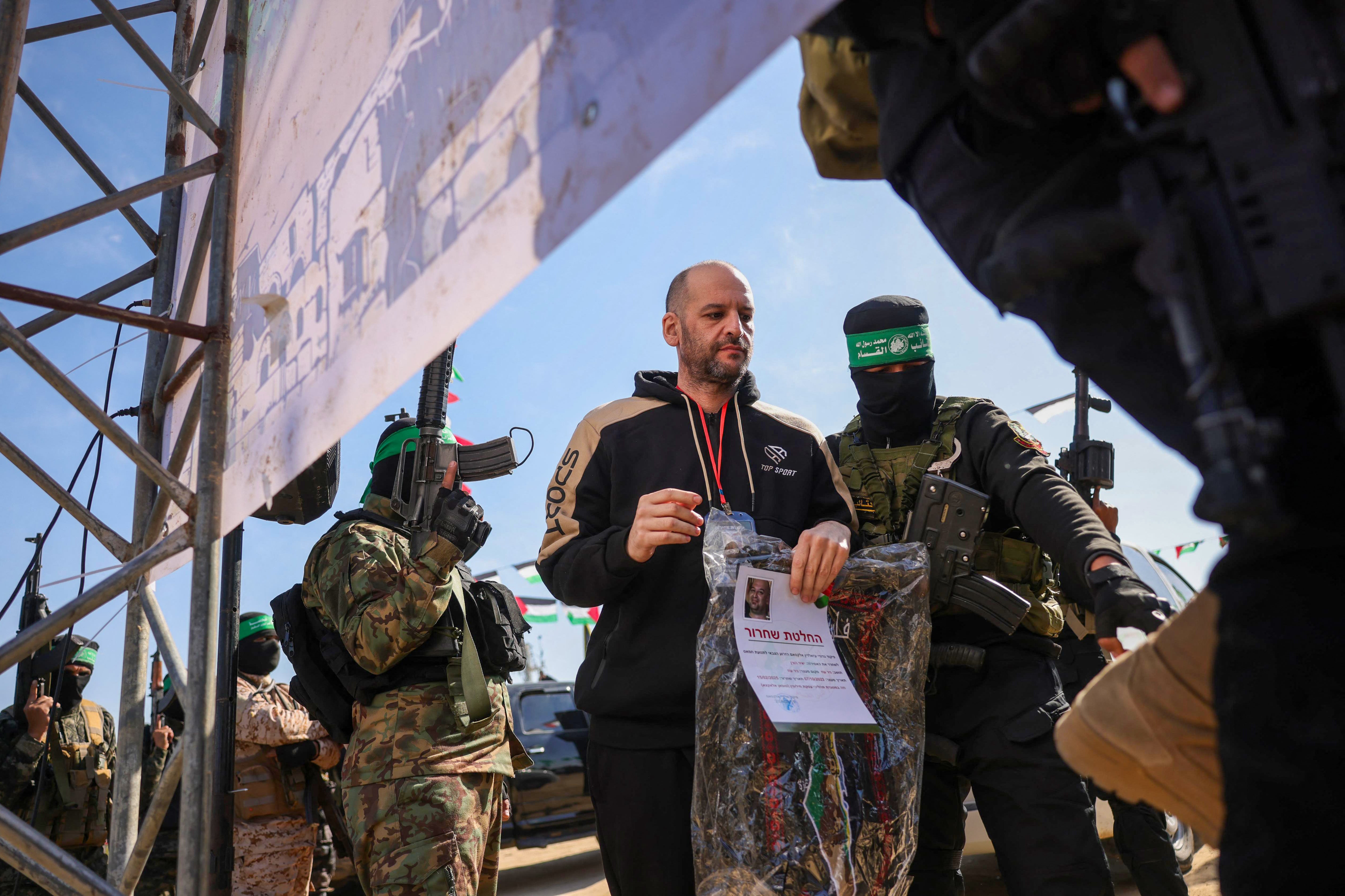 Hamasovi militanti prate izraelsko-argentinsku taocu Yair rog na pozornici prije nego što su ga predali timu Crvenog križa