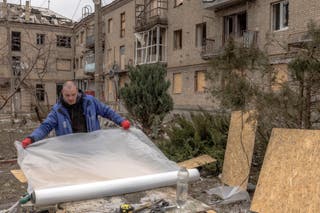 Čovjek se priprema za ukrcavanje prozora stambene zgrade oštećene granatiranjem u Kostyantynivki, u istočnoj regiji Donjecka