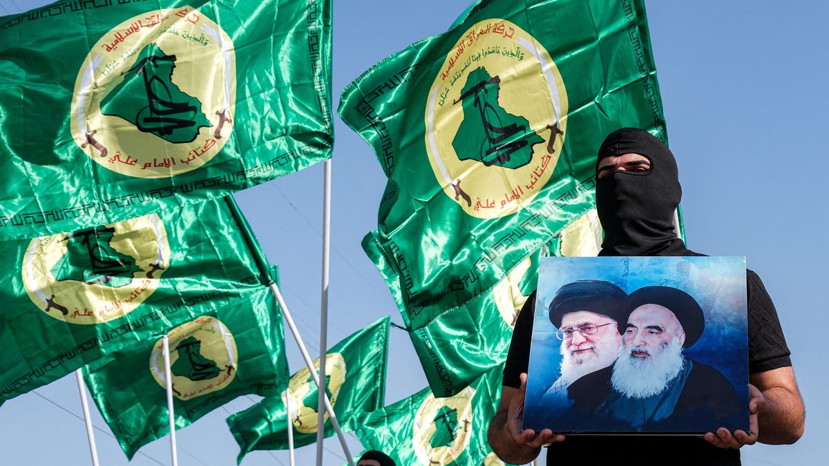 Član Islamskog pokreta Iraka drži fotografije iranskih vođa.