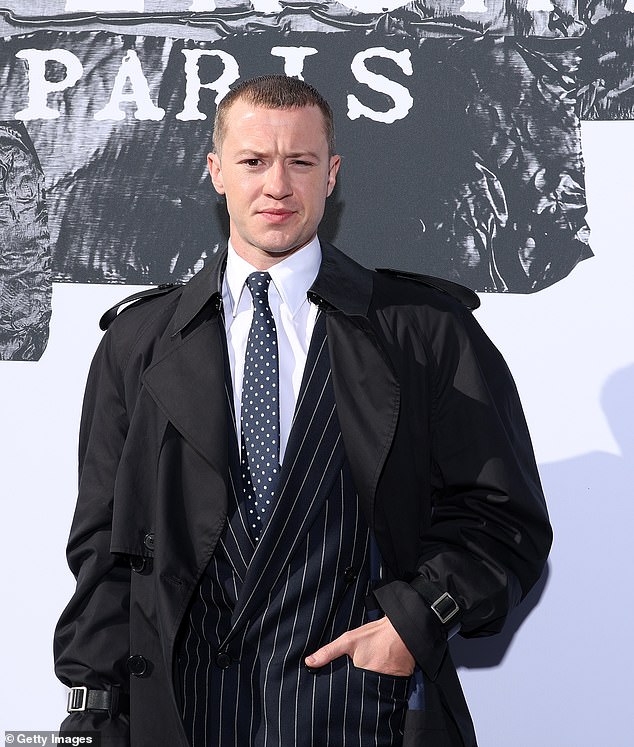 Upario je ansambl s kravatom od polka točke, dugim crnim kaputom rovova i odgovarajućim crnim i bijelim cipelama