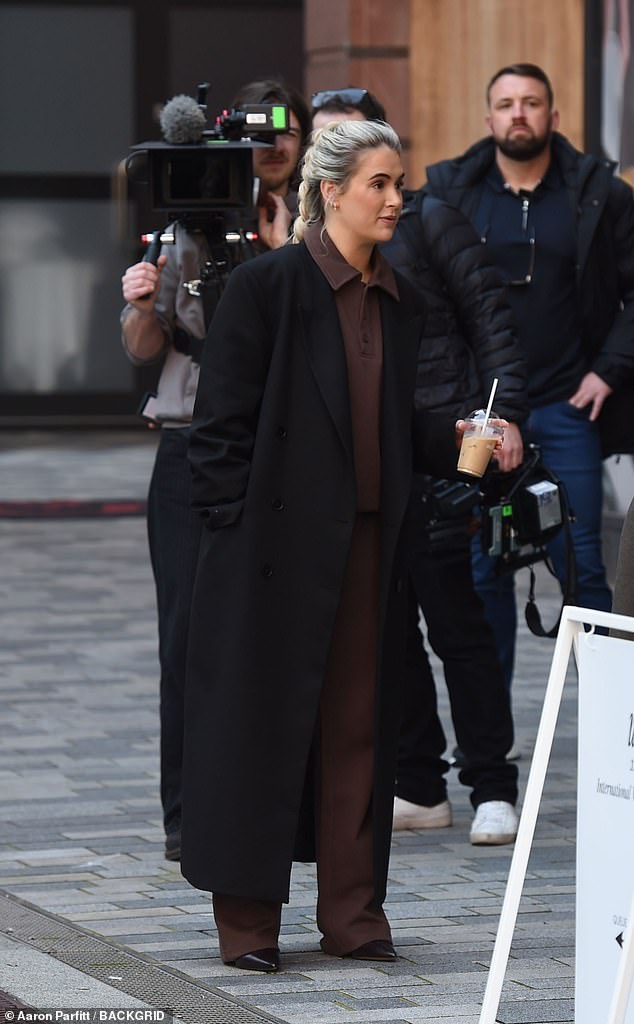 Dodajući nagovještaj o ležernosti na njezin izlet, ona je slojila svoj pametni kaput preko smeđe prevelike dnevne odjeće