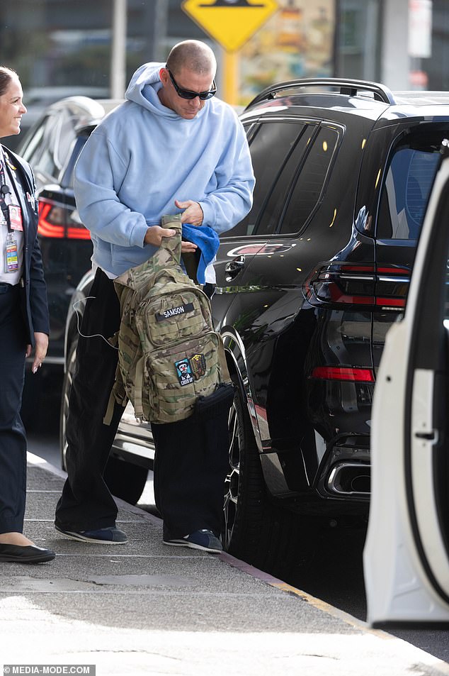 Obukao se ležerno za putovanje, noseći par vrećastih crnih traperica, plavu kapuljaču i trenere