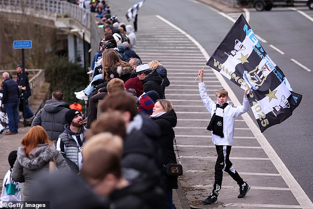 Navijač Newcastlea maše zastavom na cesti dok navijači sjede na nadvožnjaku kako bi gledali Paradu Open Top Bus Parade Parade
