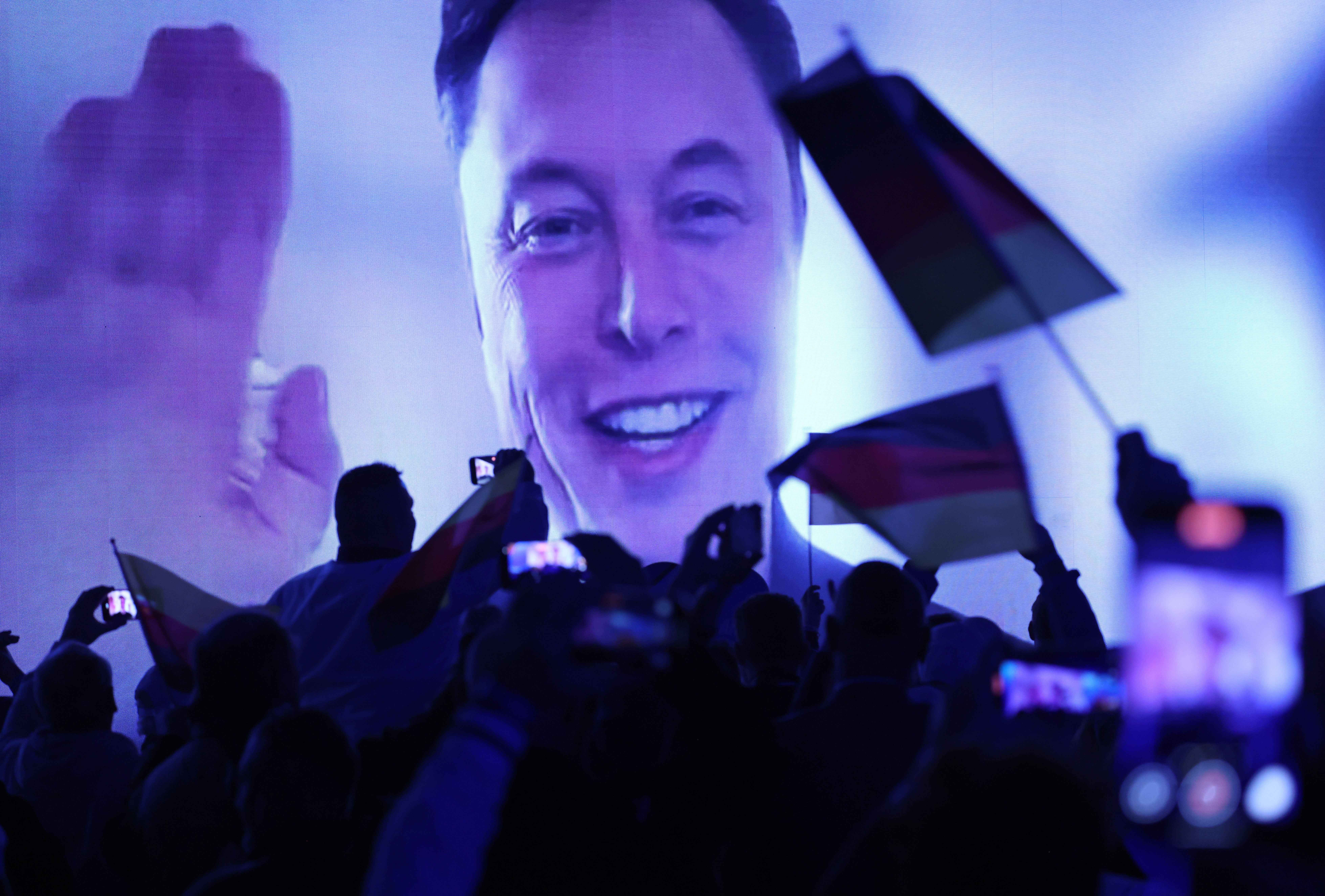 Tehnološki milijarder Elon Musk govori uživo putem video prijenosa tijekom pokretanja izborne kampanje, krajnje desne alternative za Njemačku (AFD) političku stranku dok navijači AFD-a maše njemačkim zastavama u Halleu u Njemačkoj u siječnju