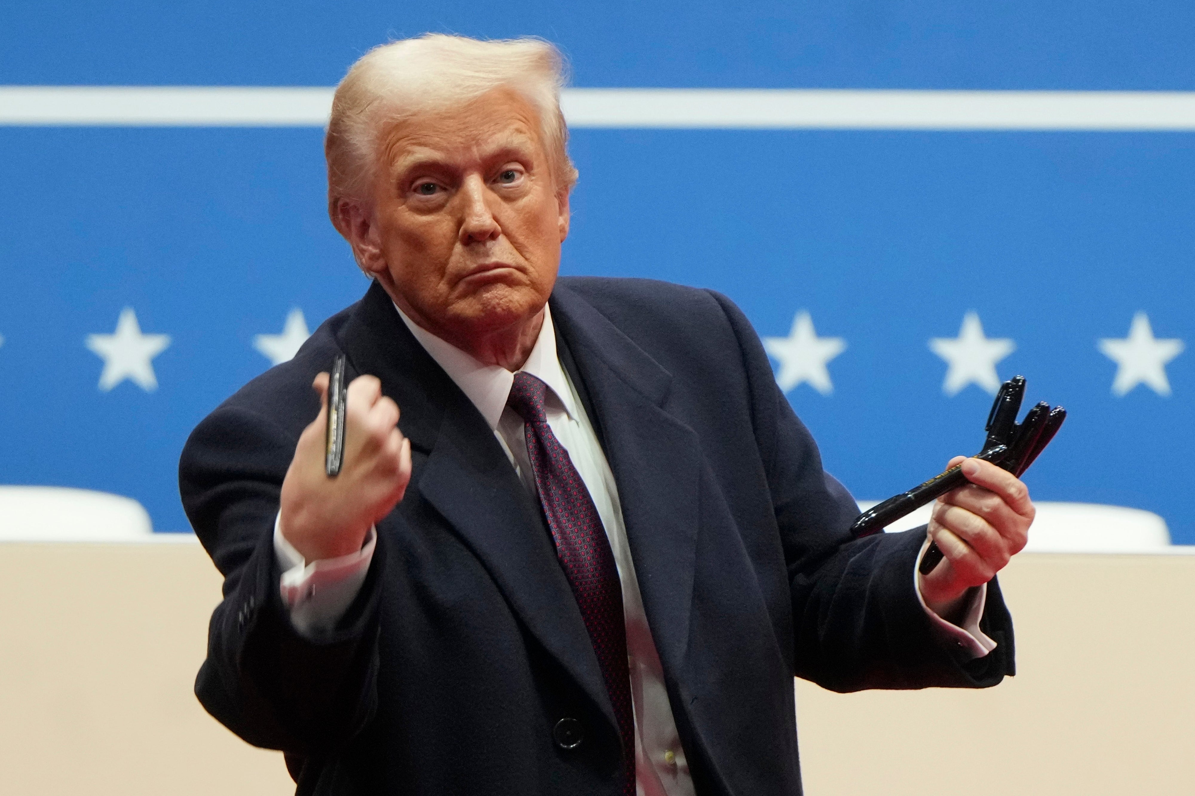 Predsjednik Donald Trump baca olovke koje je publici potpisao izvršne naredbe tijekom događanja za inauguraciju u zatvorenom prostoru u Washingtonu