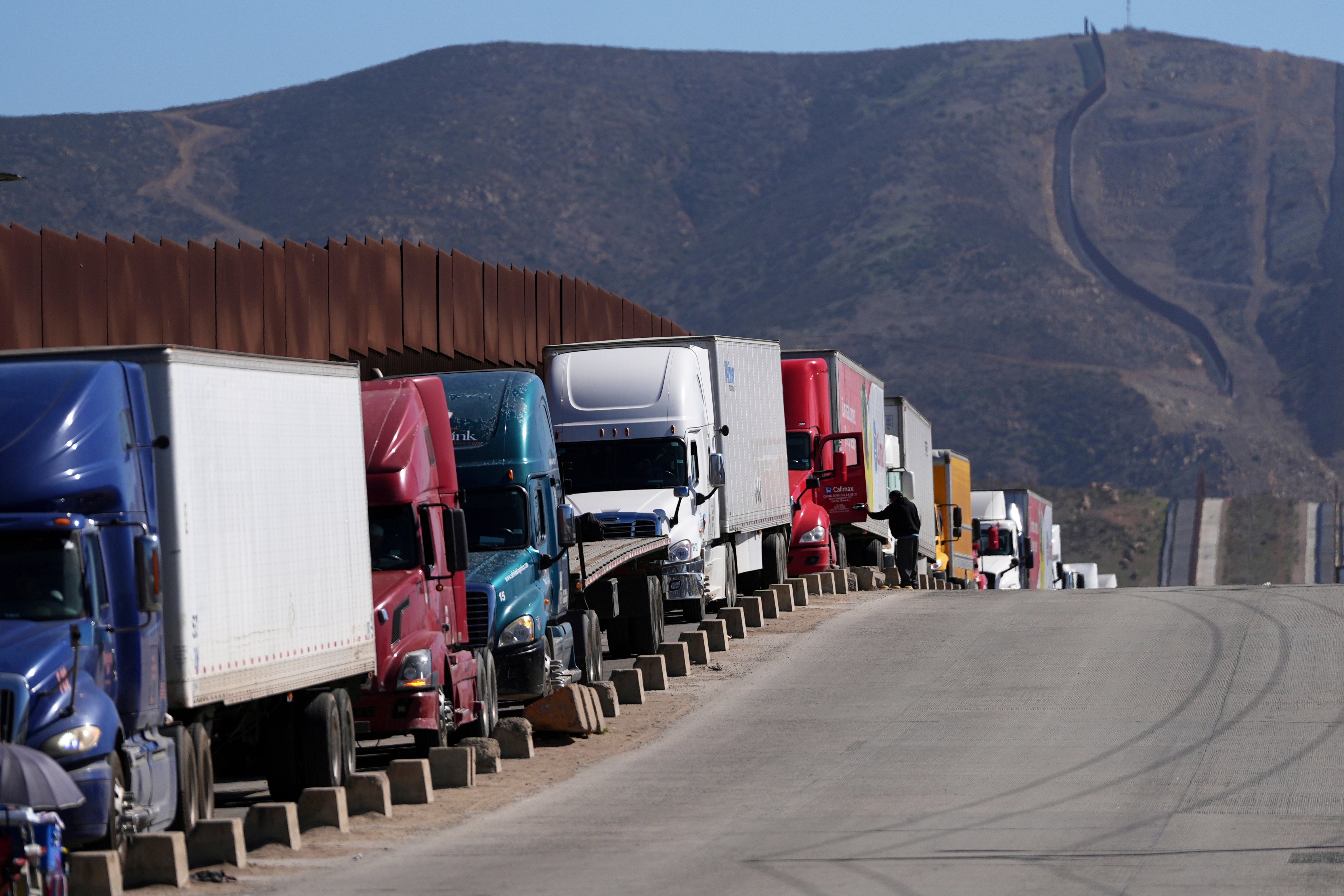 Trucks line up to cross the border into the United States as tariffs against Mexico go into effect