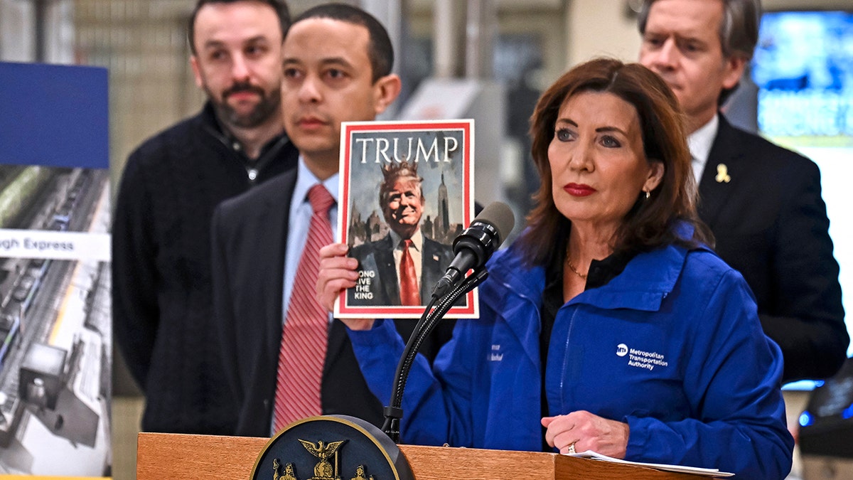 Kathy Hochul drži fotografiju Trumpa kako nosi krunu