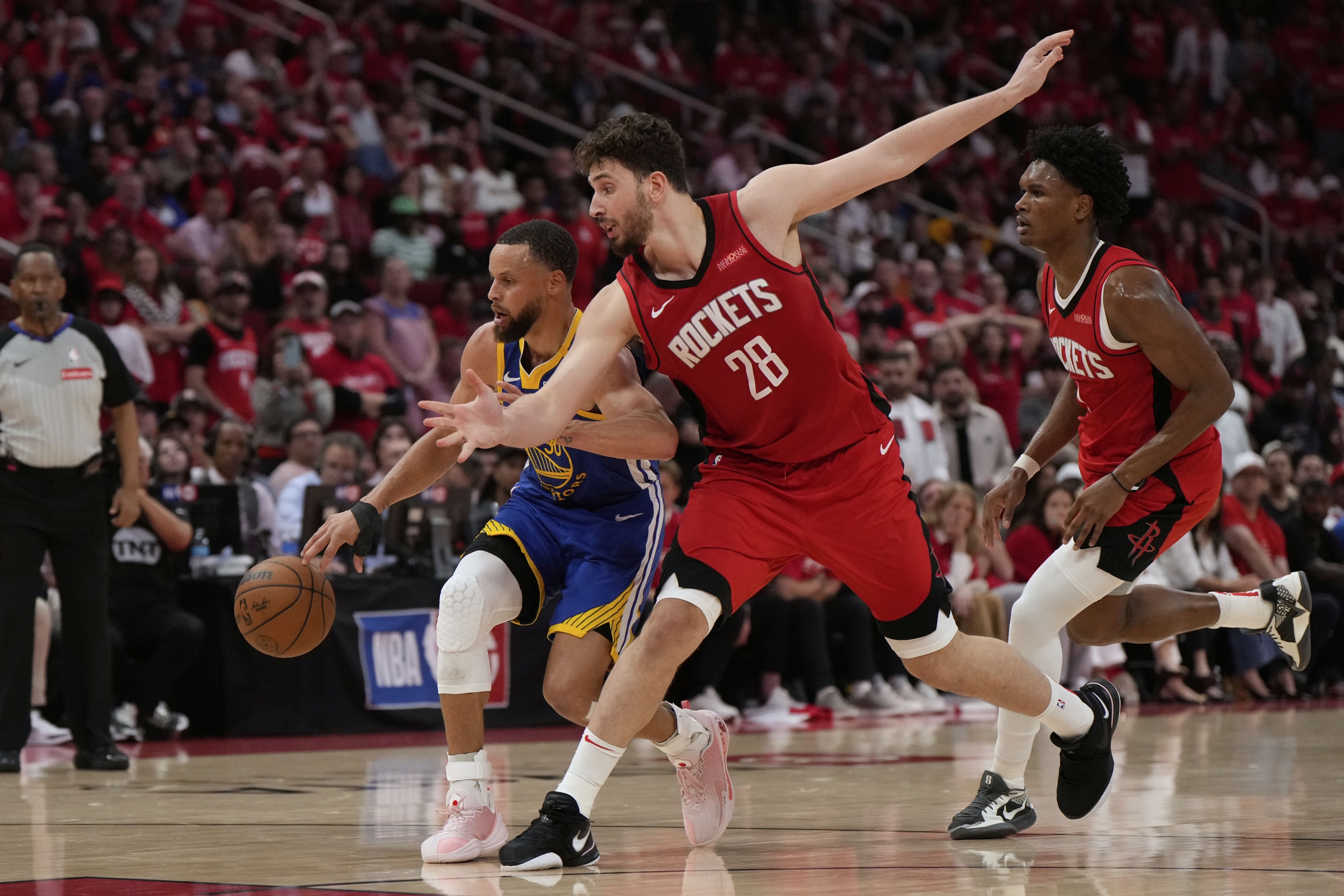 Houston Rockets Center Alperen Sengun (28) brani se protiv čuvara Golden State Warriorsa Stephena Curryja (30) tijekom drugog poluvremena igre 1 NBA košarkaške serije prvog kola u Houstonu, u nedjelju, 20. travnja 2025. (AP Photo/Ashley Landis)