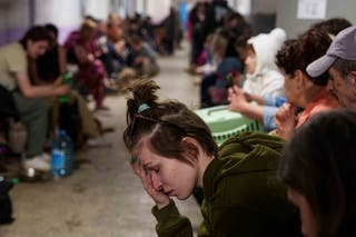 Žena sjedi u školskom podrumu koji se koristi kao sklonište nakon ruskog zračnog udara u stambenom susjedstvu u Kijevu