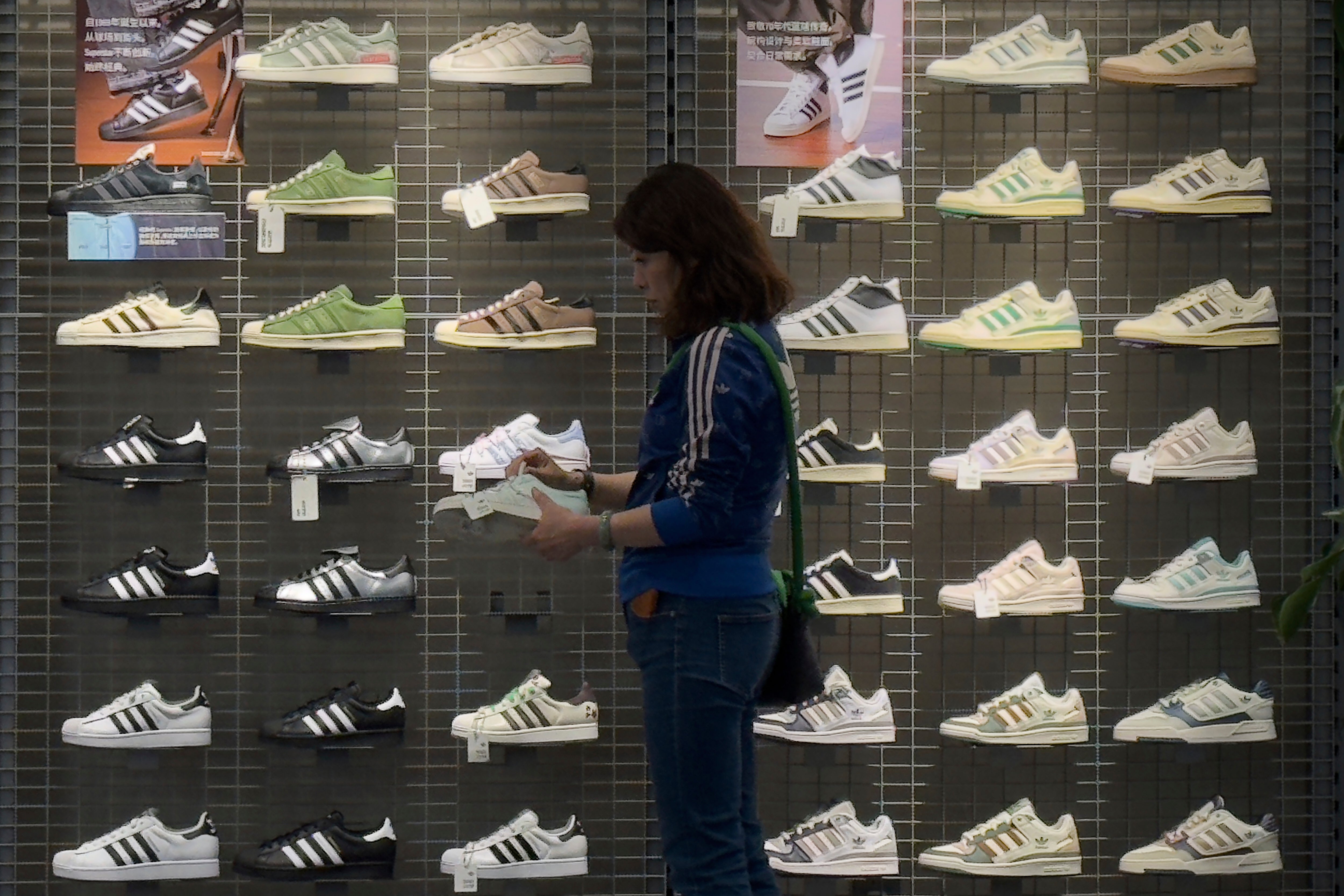 Žena isproba cipelu u trgovini Adidas Sportswear u trgovačkom centru, u Pekingu, u subotu, 12. travnja 2025. godine.