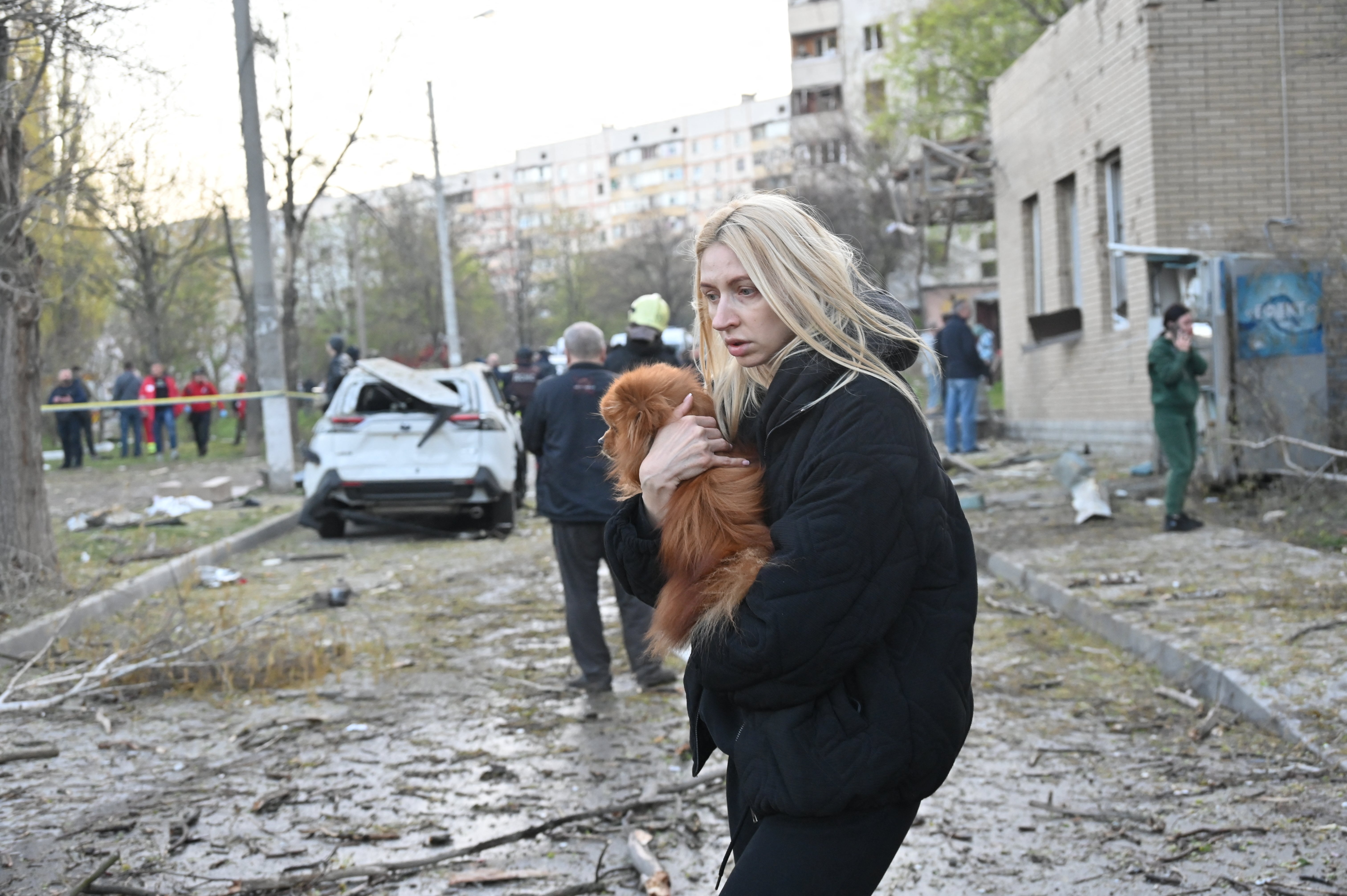Žena drži psa dok stoji izvan apartmana pogođenih u ruskim štrajkovima na Harkivu