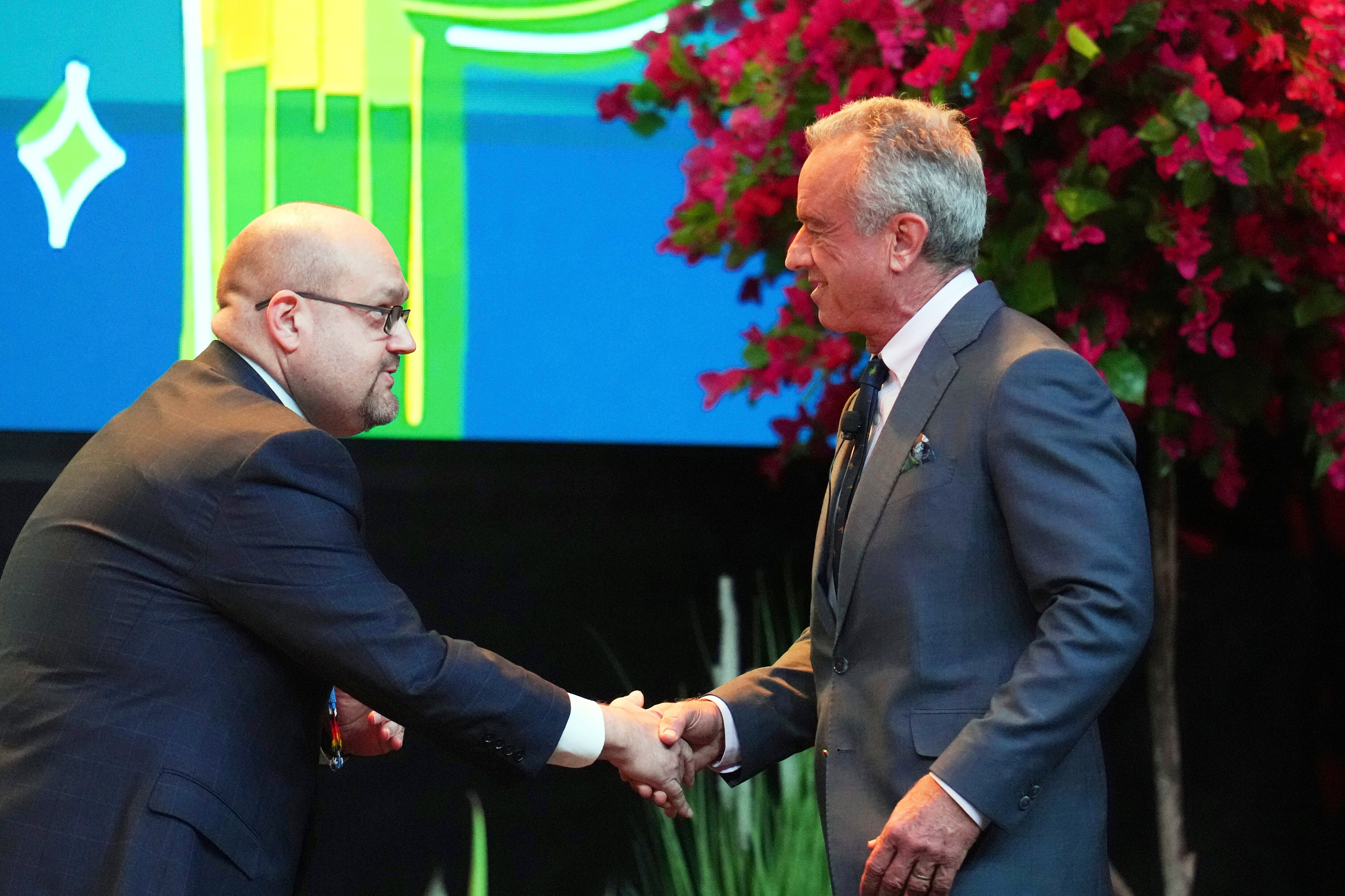 Američki zdravstveni ministar Robert F. Kennedy Jr., desno, ruka ruku s Chrisom Anoatubbyjem, potpukovnikom, Chickasaw Nation prije pohađanja na plemenskoj konferenciji o samoodređenju i samoupravljanju u utorak, 8. travnja, 2025., u Chandleru, Ariz. (AP/Ross D. Franklin)