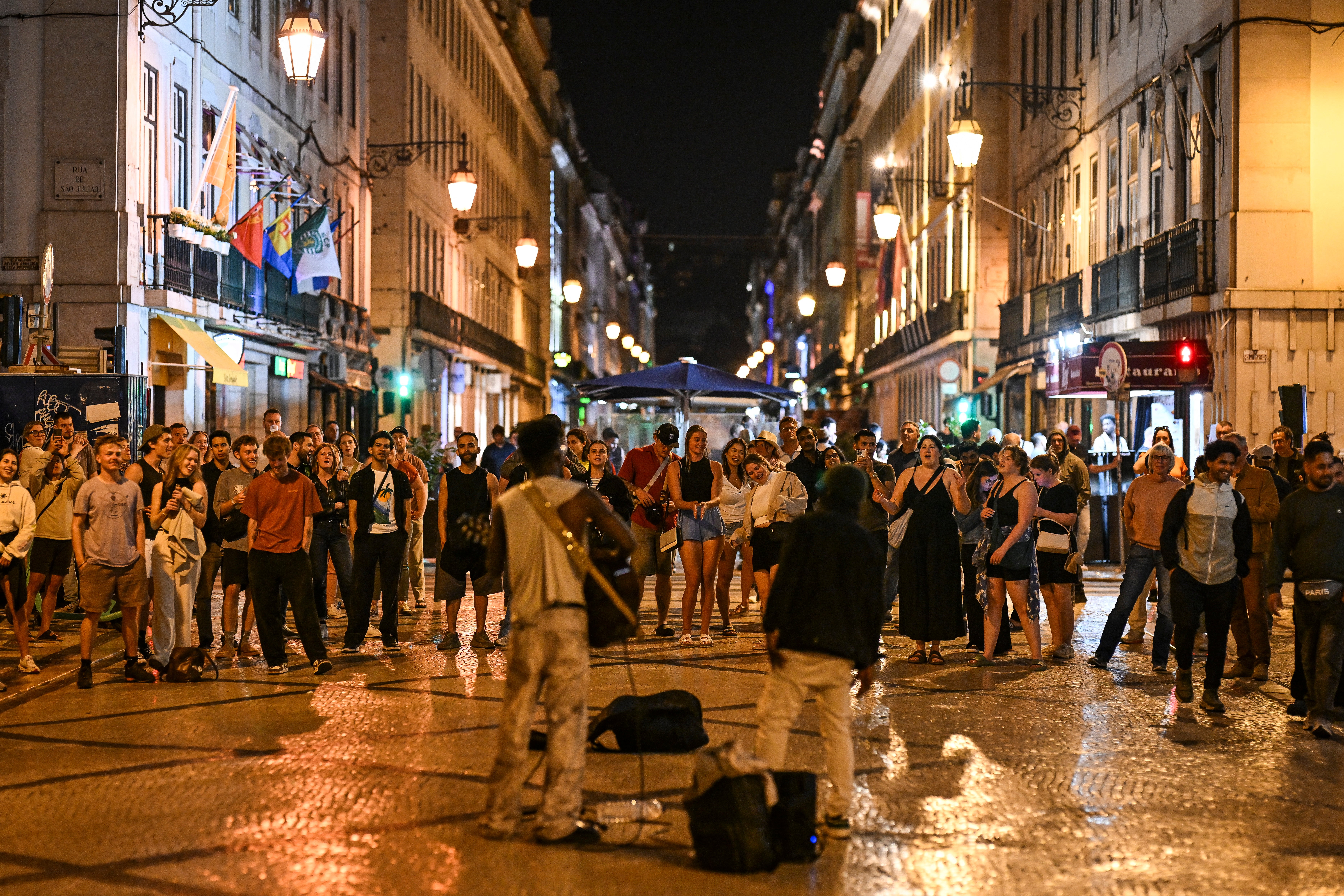 Ljudi uživaju u glazbi koju su svirali ulični umjetnici u Rua Augusta nakon što su svjetla obnovljena nakon ogromnog prekida struje koja je utjecala na cijeli Iberijski poluotok i južno od Francuske, u Lisabonu