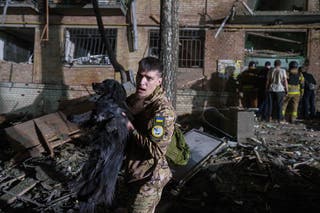 Ukrajinski vojnik nosi psa iz kuće oštećene ruskim zračnim udarom