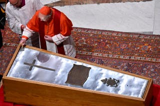 Kardinal Re posipat će lijes svetom vodom i tamjanom.