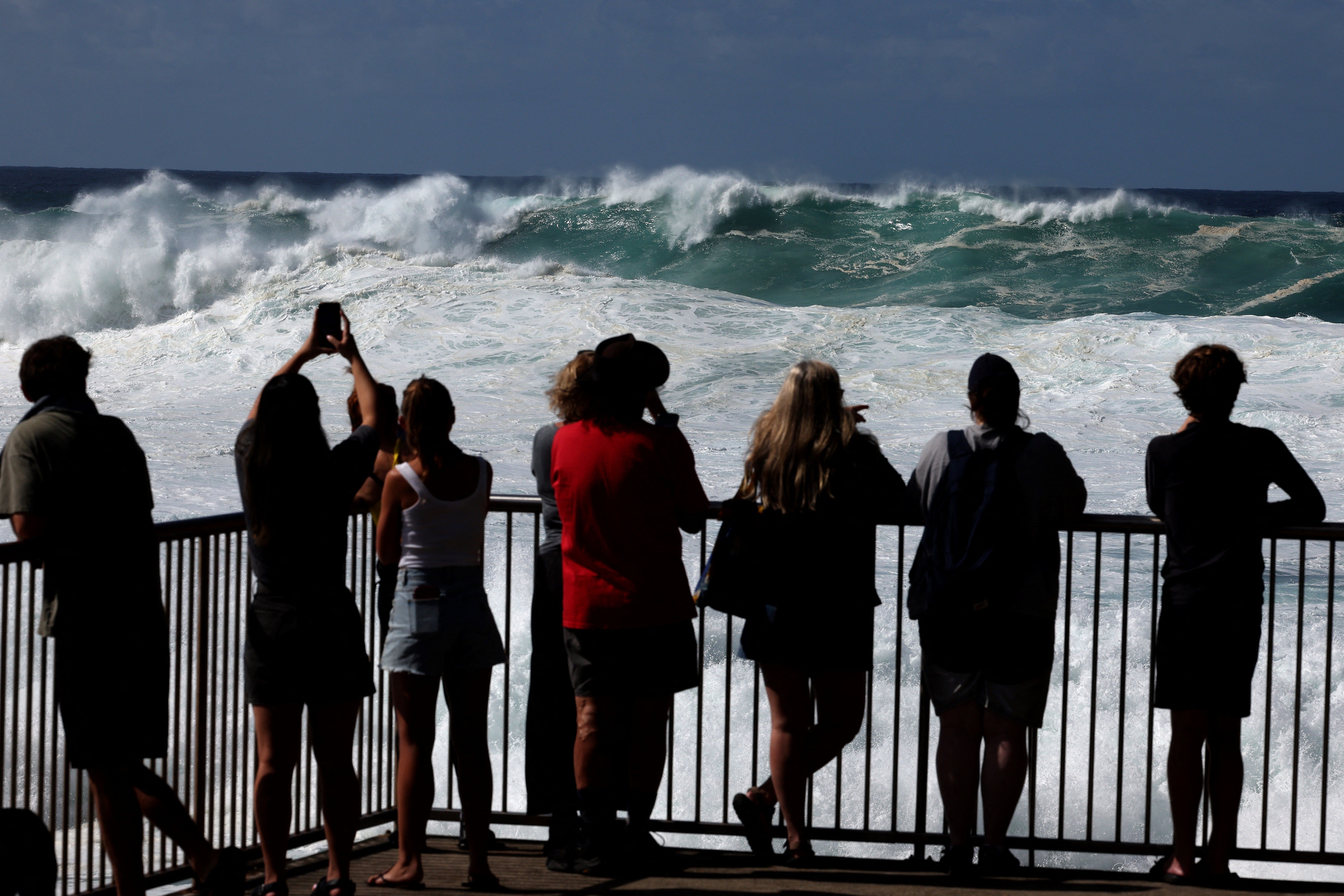 Posjetitelji gledaju kako se veliki valovi sruše protiv stijene na plaži Bronte u Sydneyu