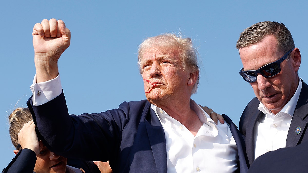 Donald Trump s krvlju na licu, drži šaku u zraku